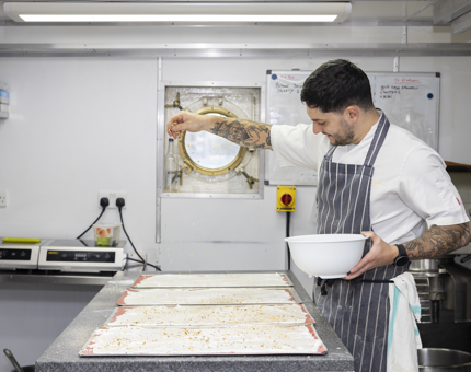 A chef is in The Royal Yacht Britannia's Galley preparing a dessert. 