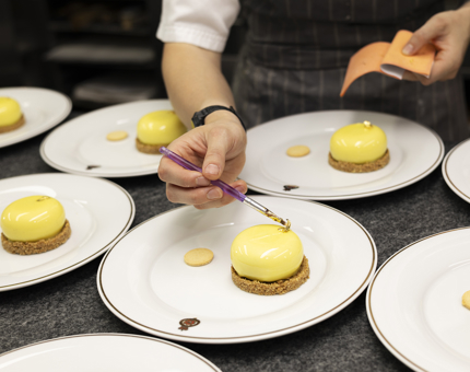 A close up of a chefs hands adding edible gold leaf to lemon cheesecakes