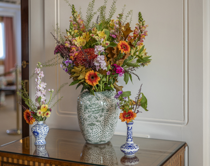 Three vases with autumnal flower arrangements in them, sitting on a table in the State Apartments. 