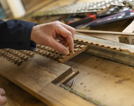 A close-up of a hand adding in new lattice details on scupper boards. 
