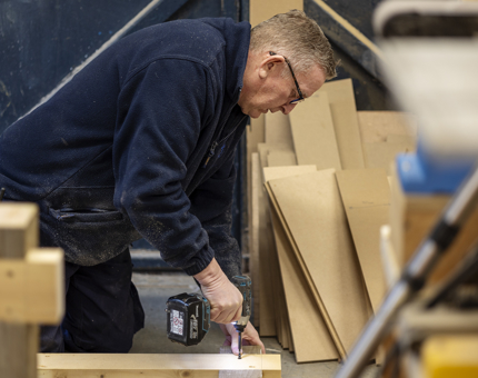 Maintenance man is drilling into a Workshop bench