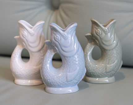 Three Gluggle Jugs. they are shaped like fish and come in three colours, white, pale blue and pale grey.