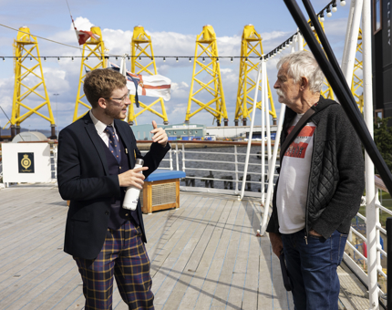 A Visitor Assistant Chatting To A Visitor On Britannia's Verandah Deck in the Port of Leith. 