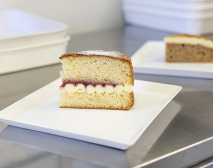 A slice of Victoria sponge and a slice of carrot cake are on plates, ready to be served in the Tearoom. 