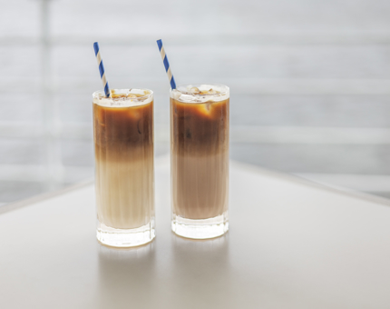Two iced drinks with blue and white straws. 