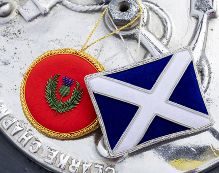 Two Scottish themed hanging decorations. One is a blue and white Scotland flag, the other a red circle with a thistle on. 