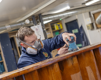 A Maintenance man sanding down dowels that were put in place to secure a set of steps from the Bridge. 