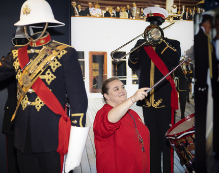 A Housekeeper is in Britannia's Visitor Centre dusting mannequins in Naval band uniforms. 