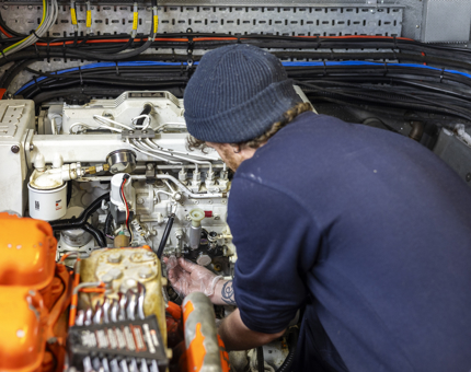 A Maintenance team member is working on the engines from a small boat in the Port of Leith. 