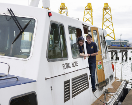 Two Maintenance men posing for a photo aboard a small boat in the Port of Leith. 