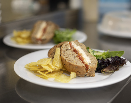 Sandwiches on plates with crisps and salad, ready to be served in the Royal Deck Tearoom. 