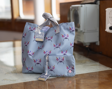 A blue bag and wallet with a highland cow design on it.