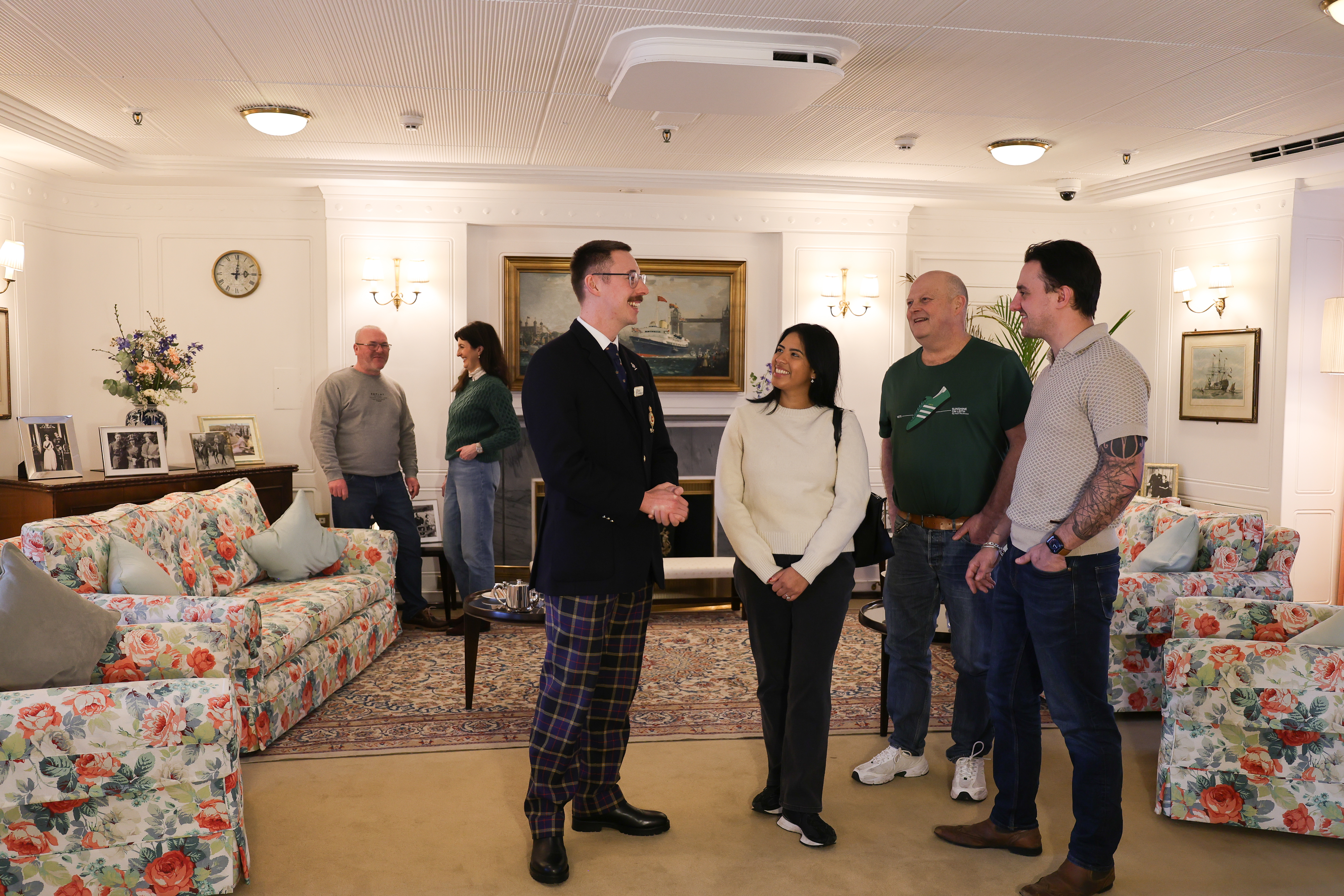 A guide is talking to guests in the State Dining Room aboard The Royal Yacht Britannia in Leith.