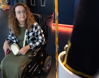 A woman in a wheelchair is looking at a military uniform in The Royal Yacht Britannia's Visitor Centre.