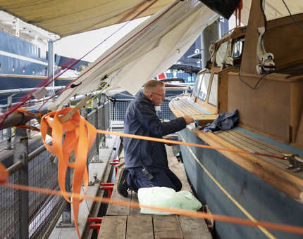 A maintenance team member caulking the Royal Barge in the Port of Leith. 