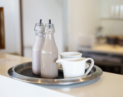 Two flavoured milks on a tray with a milk jug and tea cup. 