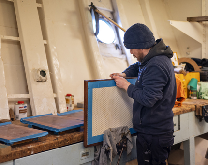 A Maintenance man sanding a step from the Royal Barge of The Royal Yacht Britannia. 