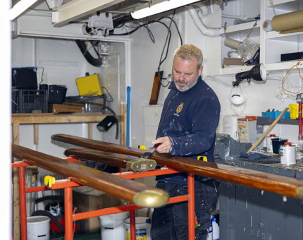 A member of the Maintenance team is varnishing handrails. 