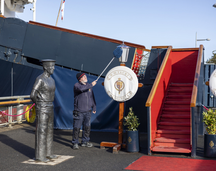 A Facilities Officer is on the Quayside cleaning the Royal Brow with a duster in the Port of Leith. 