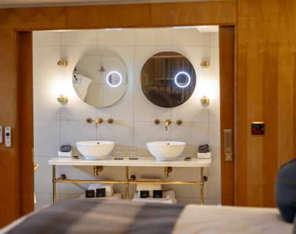 A cabin aboard Fingal in the Port of Leith. From the bed you can see the bathroom with double sinks and two round mirrors. 