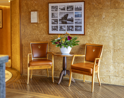 Two chairs flanking a table with a vase of flowers in Fingal's Reception. 