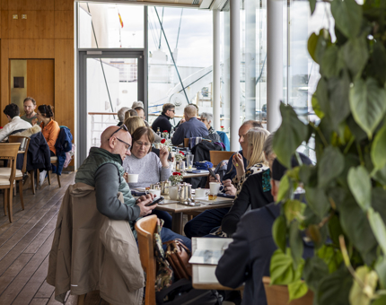 Visitors sitting at tables and enjoying a break from their tour in the Royal Deck Tearoom. 