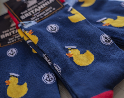 Navy blue socks with illustrations of ducks wearing captains hats and anchors. 