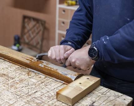 A close up of a Maintenance man's hands, he is removing varnish from a handrail from Fingal Hotel