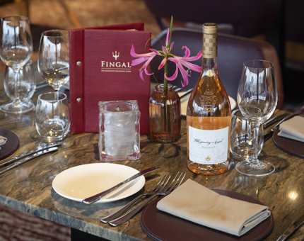 A table in the Lighthouse Restaurant & Bar aboard Fingal Hotel in Leith is set for dinner. There is a bottle of wine on the table.