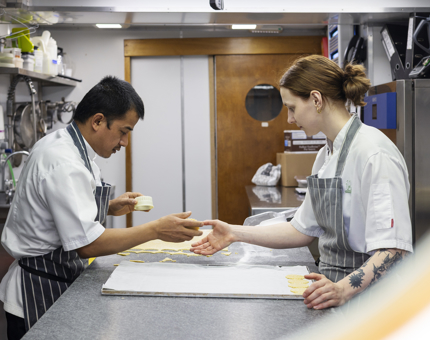 Two chefs are in the Galley aboard Britannia making pastry. 