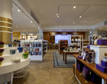 Inside the new Britannia Shop. There are wooden tables, a central round pillar with gold rings around it, and lots of souvenirs and gifts.