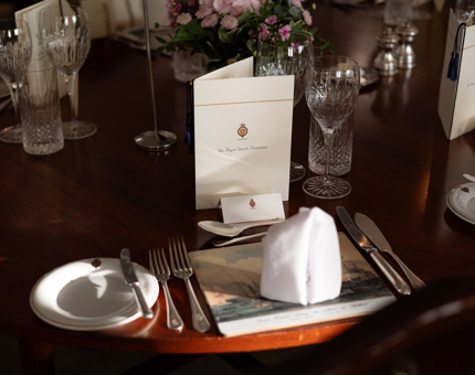 A close up of a Britannia table setting with a menu and place card in the State Dining Room. 