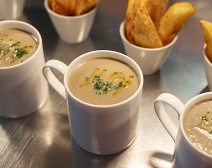 Three mugs of mushroom soup and three bowls of potato wedges on a bench in the Galley aboard Britannia. 