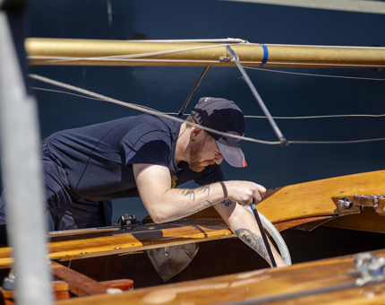 A Maintenance team member pumping rain water from a small sailing yacht.