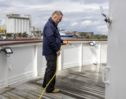 A member of the Maintenance team is hosing the deck. 