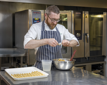 A chef is in the Galley preparing mackerel quenelles as part of the starter for an evening event aboard Britannia. 