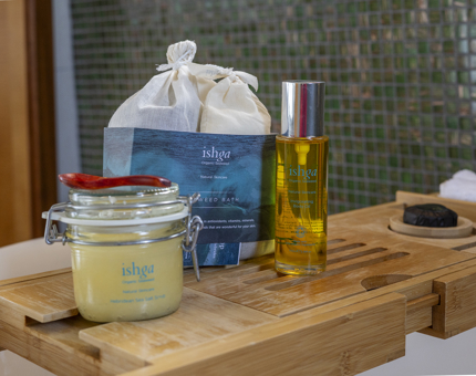 A wooden tray is placed over a bathtub aboard Fingal. There are relaxing bath products placed on it, branded ishga. 