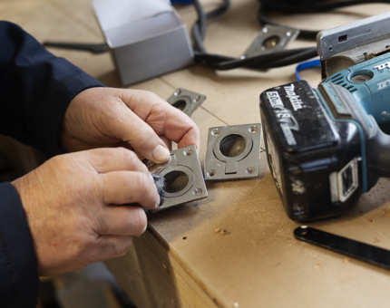A close-up of hands polishing flush ring pulls. 