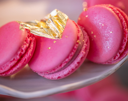 A plate of pink macarons with gold leaf. 