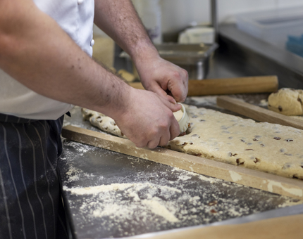 A close up of a chef making fruit scones. 