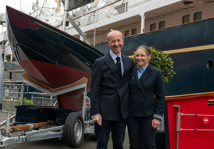 two people standing in front of a sailboat
