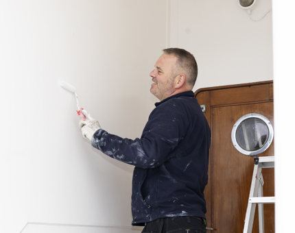 A man is applying a coat of white paint, The Royal Yacht Britannia. 