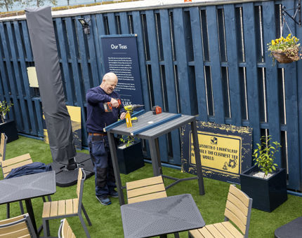 A Facilities Officer is preparing to attach signage at Tea on the Quay, next to The Royal Yacht Britannia. 