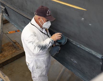 A Yottie sanding the Royal Barge located on Britannia's quayside. 